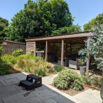 The landscaping in this garden includes porcelain patio, wood pergola and various ornamental grasses